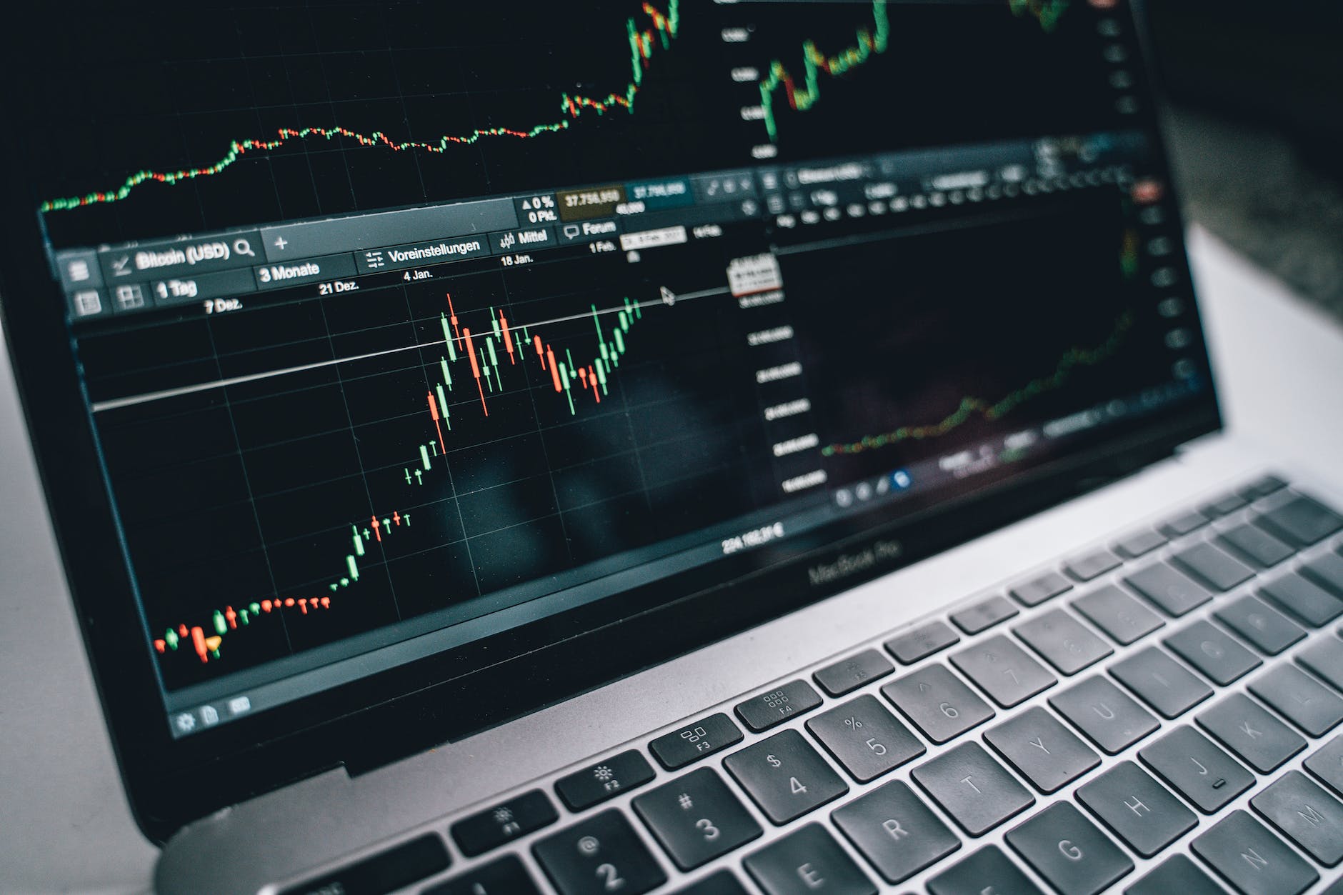 black and silver laptop with stock market display on screen